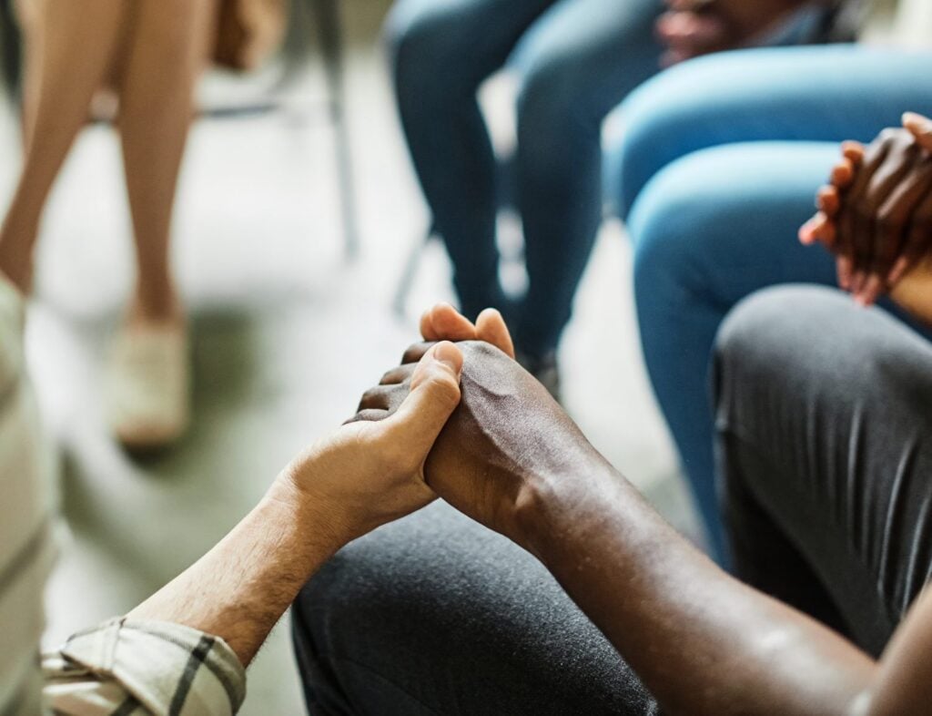 focused short on hands of group therapy members